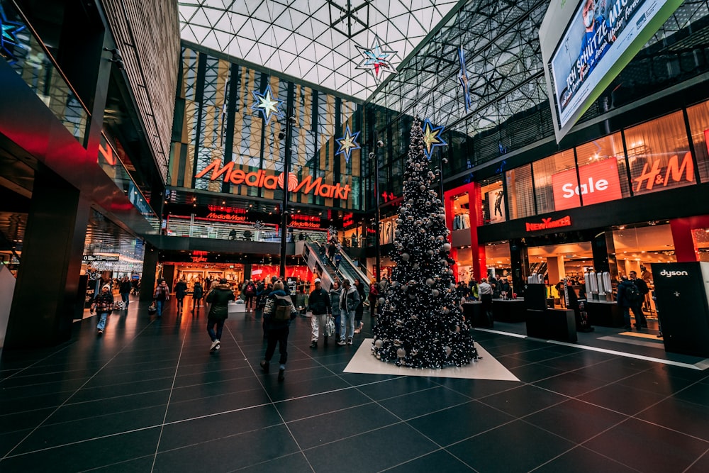 a christmas tree in a shopping mall with people walking around