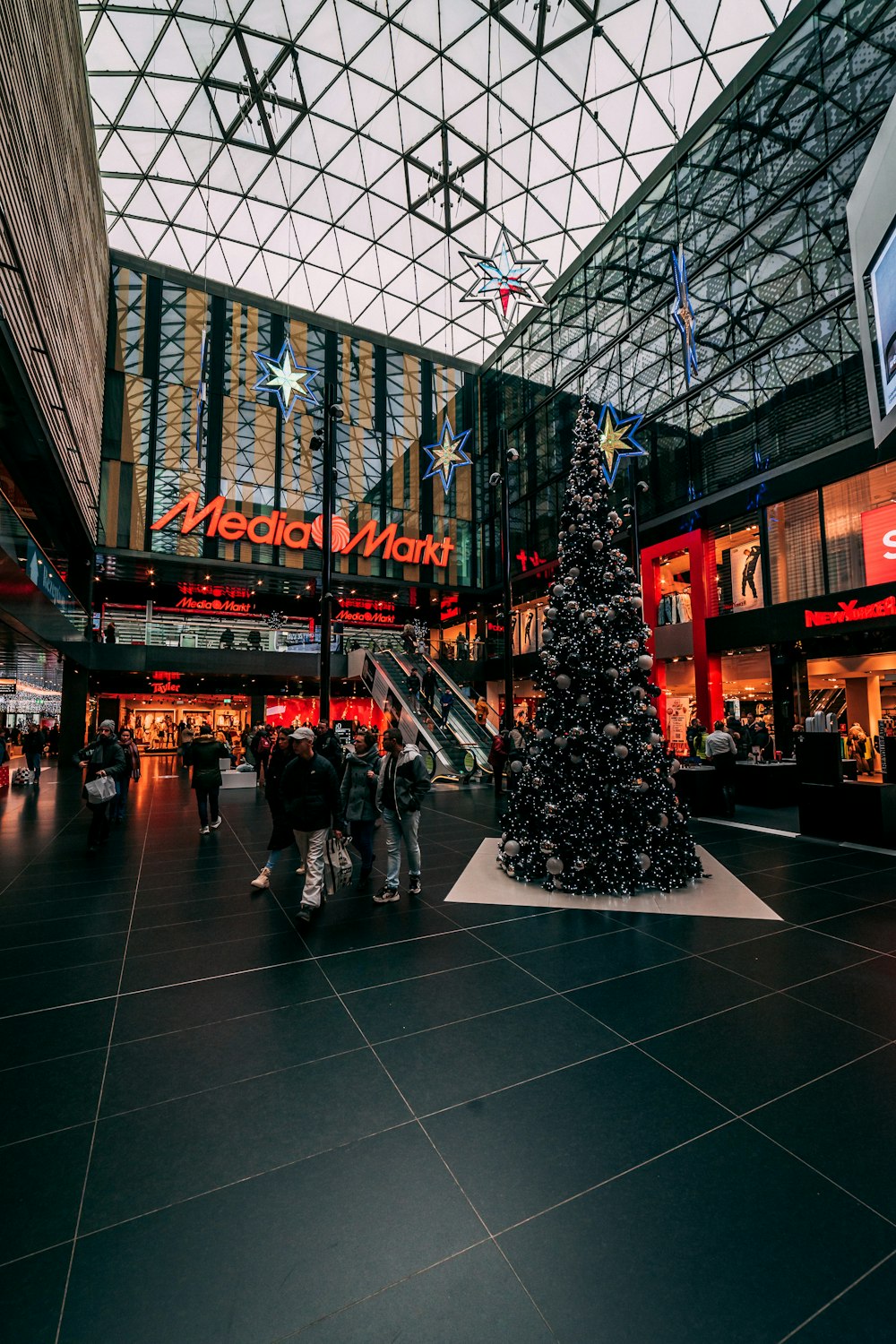 a christmas tree in a shopping mall with people walking around