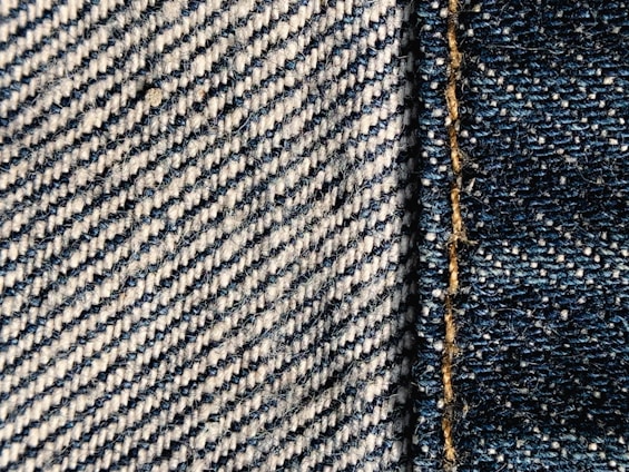 A close-up of hands stitching premium denim fabric, highlighting craftsmanship.
