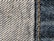 Close-up view of denim fabric showcasing a detailed weave pattern in blue and white. A seam with visible stitches runs vertically on the right side, highlighting the texture and craftsmanship.