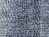 A close-up view of blue denim fabric, showcasing the intricate weave pattern and texture of the material.