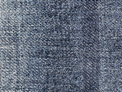 A close-up view of blue denim fabric, showcasing the intricate weave pattern and texture of the material.
