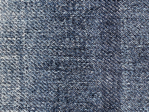 A close-up view of blue denim fabric, showcasing the intricate weave pattern and texture of the material.