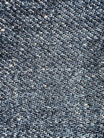 Close-up view of a textured denim fabric, showcasing a weave of blue and white threads.