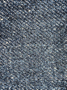 Close-up view of a textured denim fabric, showcasing a weave of blue and white threads.