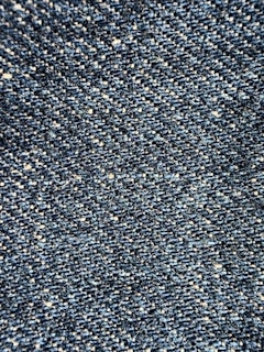 Close-up view of a textured denim fabric, showcasing a weave of blue and white threads.