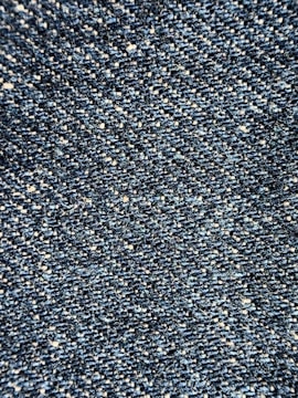 Close-up view of a textured denim fabric, showcasing a weave of blue and white threads.