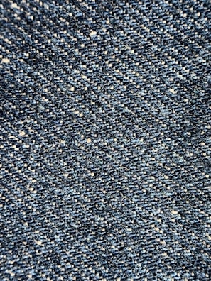 Close-up view of a textured denim fabric, showcasing a weave of blue and white threads.