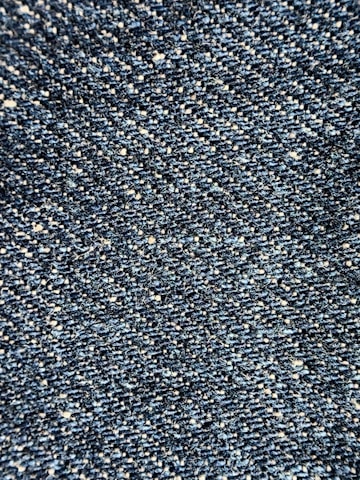 Close-up view of a textured denim fabric, showcasing a weave of blue and white threads.