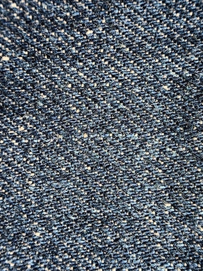 Close-up view of a textured denim fabric, showcasing a weave of blue and white threads.