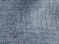 A close-up of blue denim fabric showing a detailed weave pattern with variations in shading and texture.
