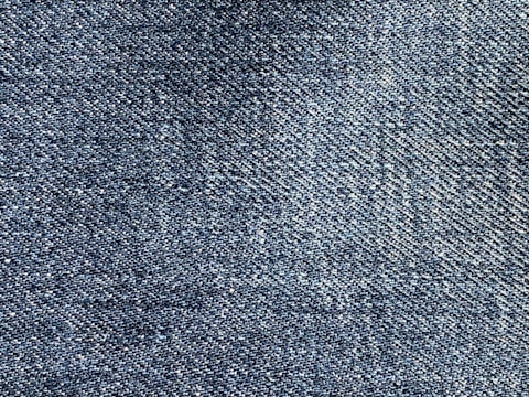 A close-up of blue denim fabric showing a detailed weave pattern with variations in shading and texture.