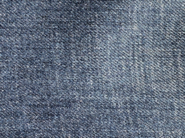 A close-up of various denim fabric swatches in different shades and textures, neatly arranged.