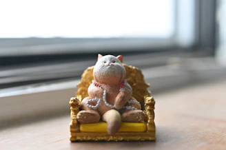 Happy cat lounging inside a royal teak palace cat house with golden accents