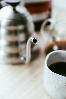 A sleek stainless steel coffee jug on a wooden table.