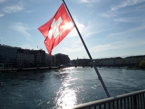 a red and white flag flying over a body of water