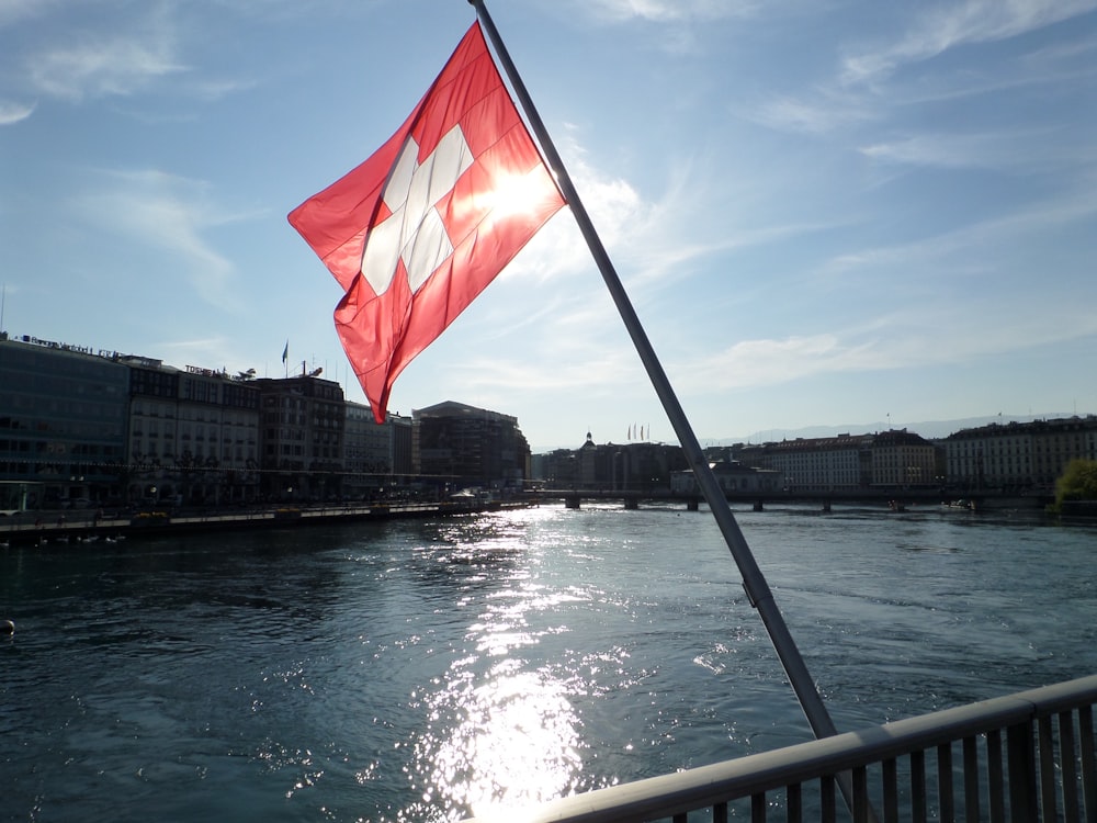 a red and white flag flying over a body of water
