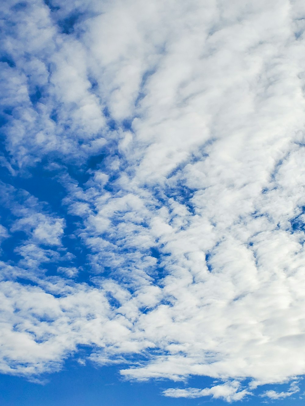 a plane flying through a cloudy blue sky