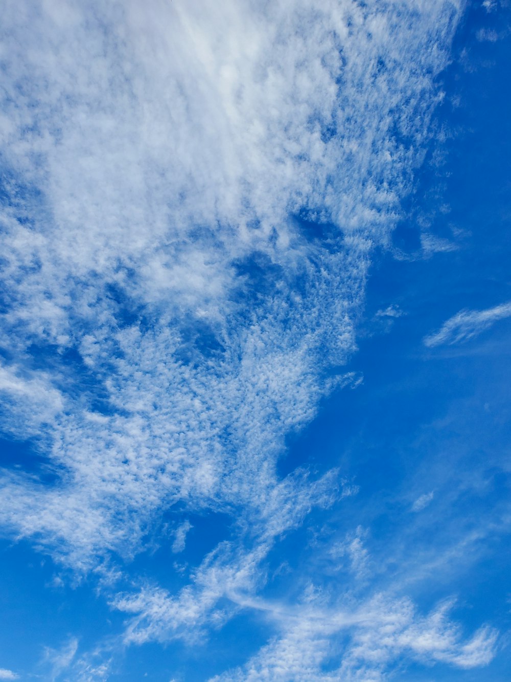 a blue sky with white clouds and a plane in the distance