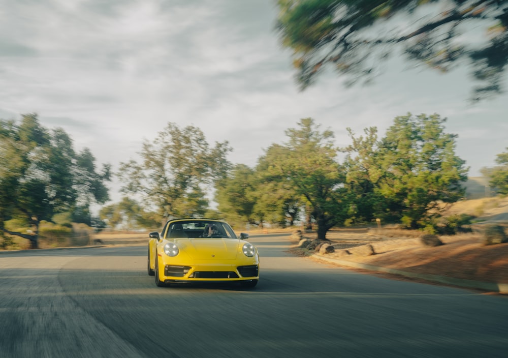 a yellow sports car driving down the road