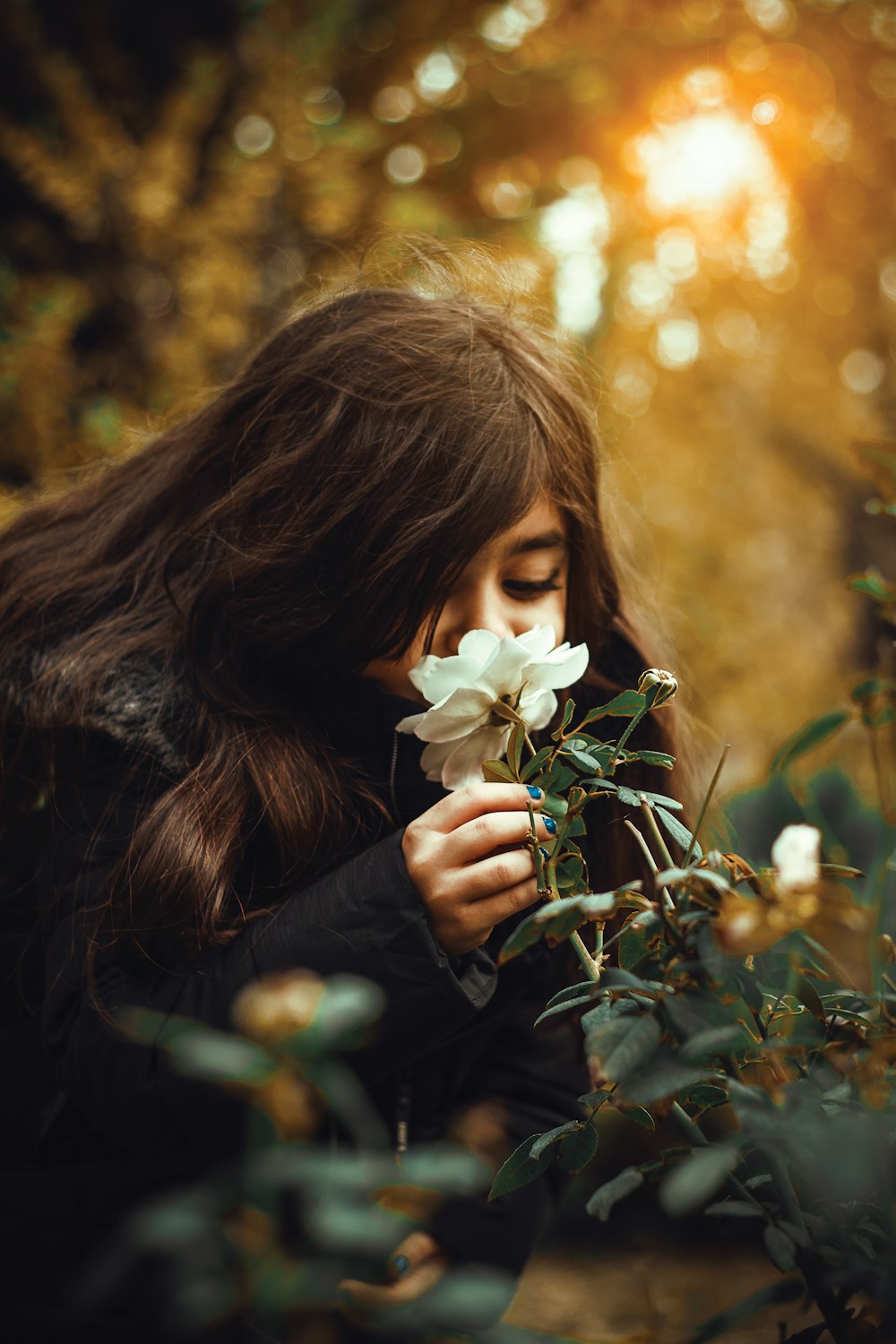 a woman smelling a flower in a forest