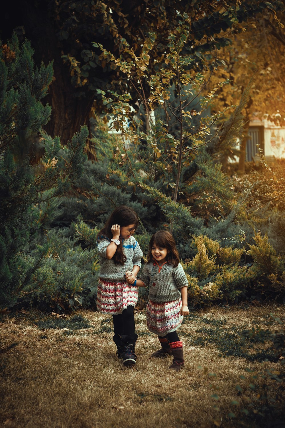 two little girls standing next to each other in a forest