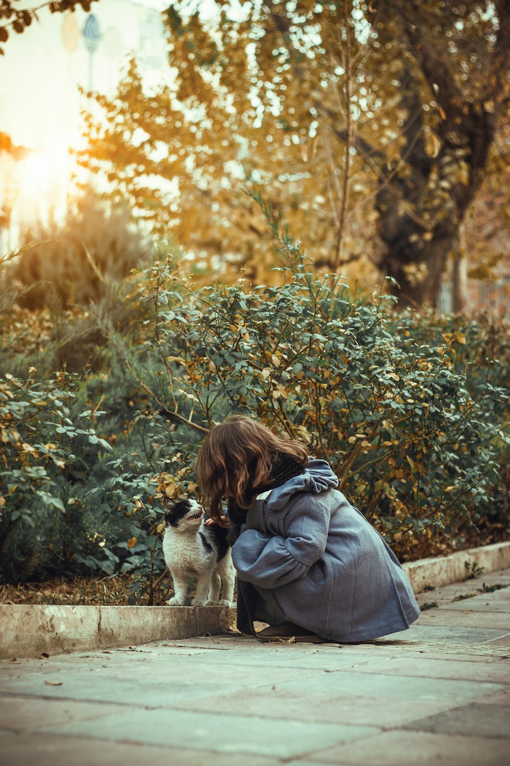 a woman kneeling down next to a cat