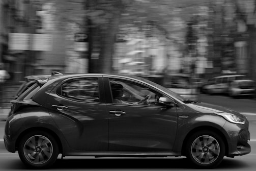 Close-up of a sleek compact car driving through busy urban traffic.