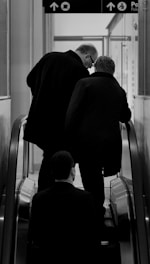 a couple of men riding down an escalator