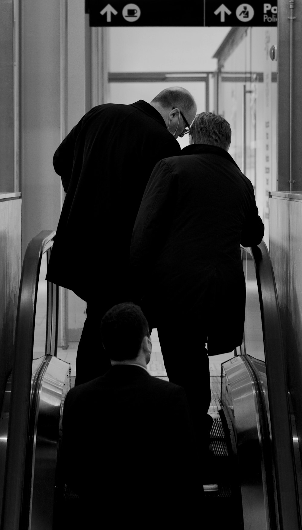 a couple of men riding down an escalator