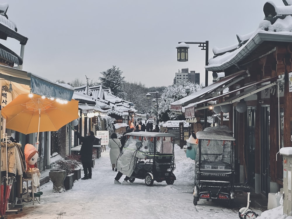 a couple of people walking down a snow covered street