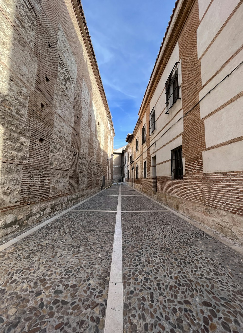 a narrow street with cobblestones and a building in the background