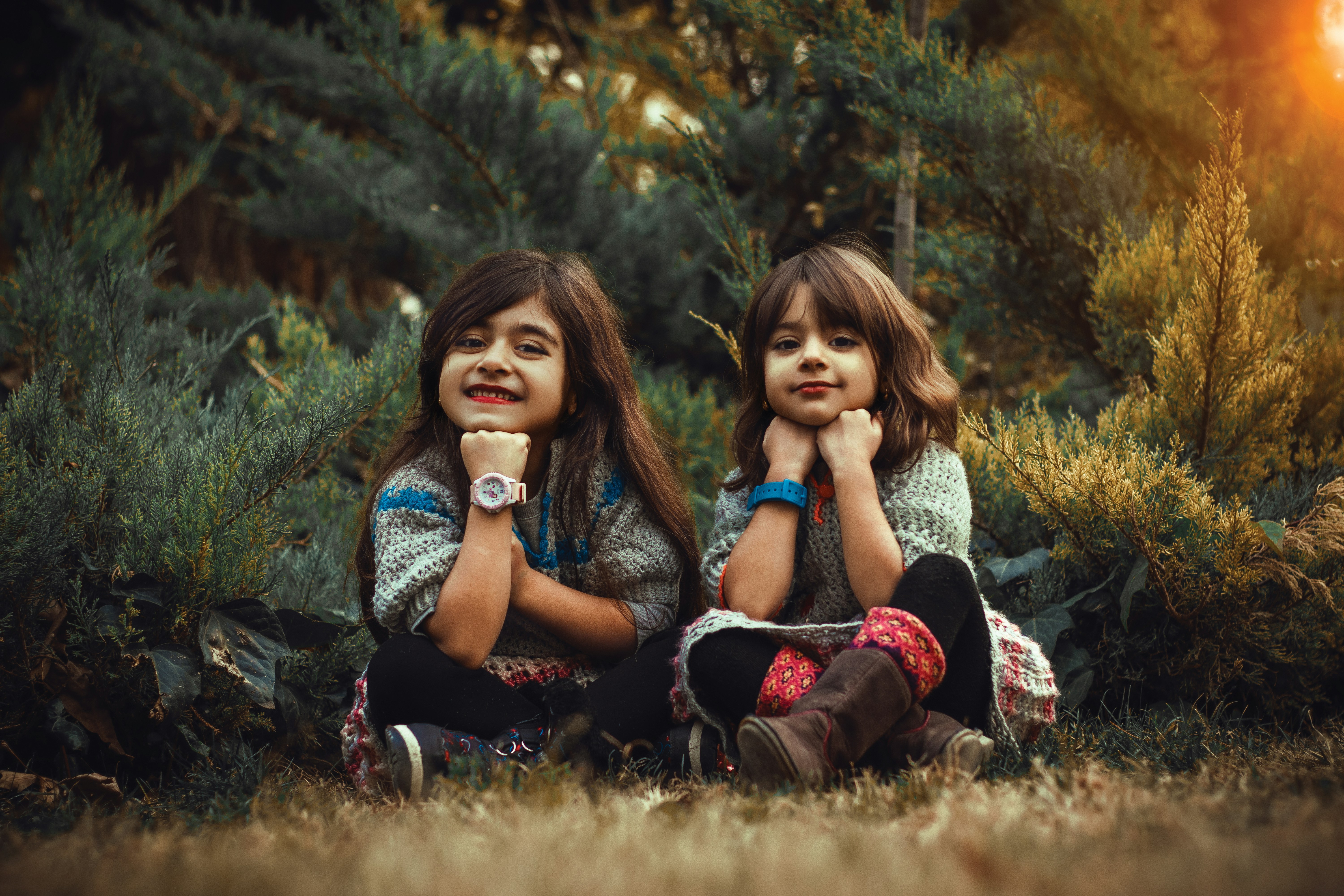duas meninas sentadas no chão na frente das árvores