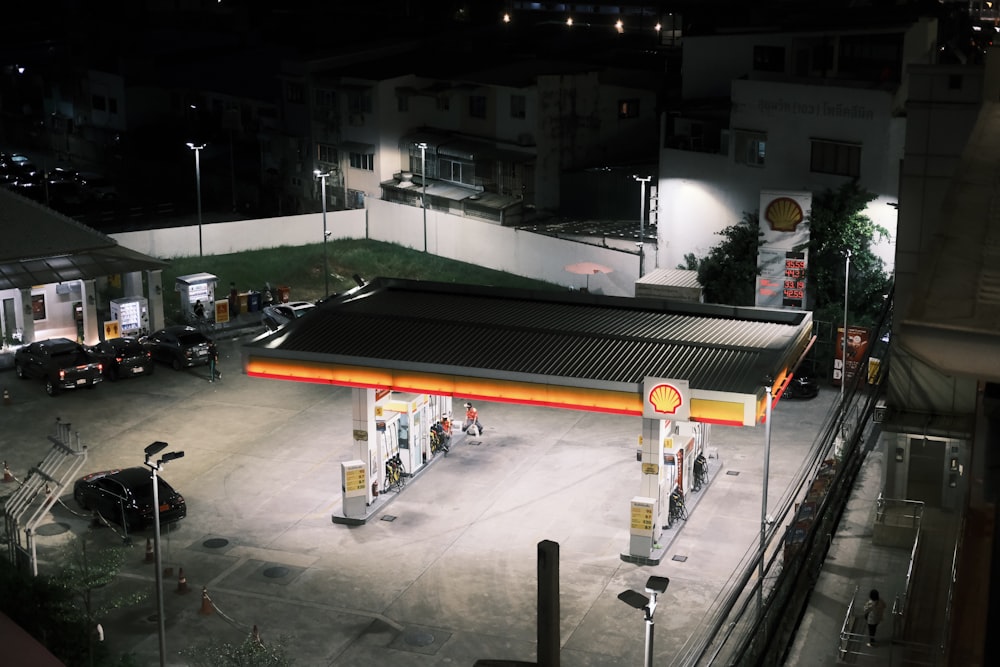 a gas station at night with cars parked in the lot