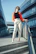 A confident woman wearing stylish trousers standing on a sunny Sharjah street.