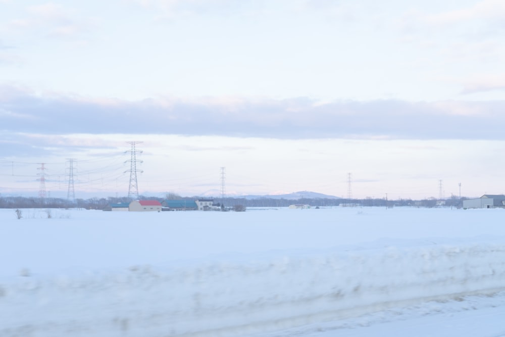 a snow covered field with power lines in the distance