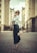 A stylish woman wearing a flowing pastel dress stands gracefully on a sunlit street, showcasing the latest fashion trends.