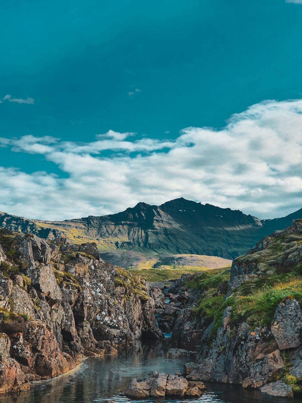 a body of water surrounded by mountains under a cloudy sky