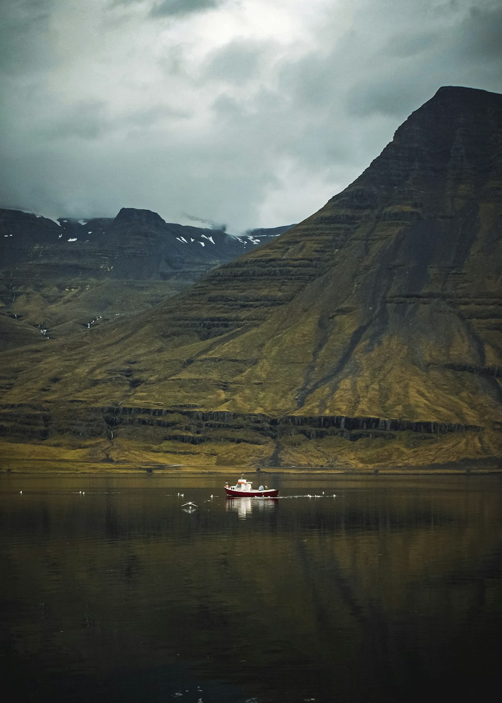 a boat floating on top of a lake next to a mountain