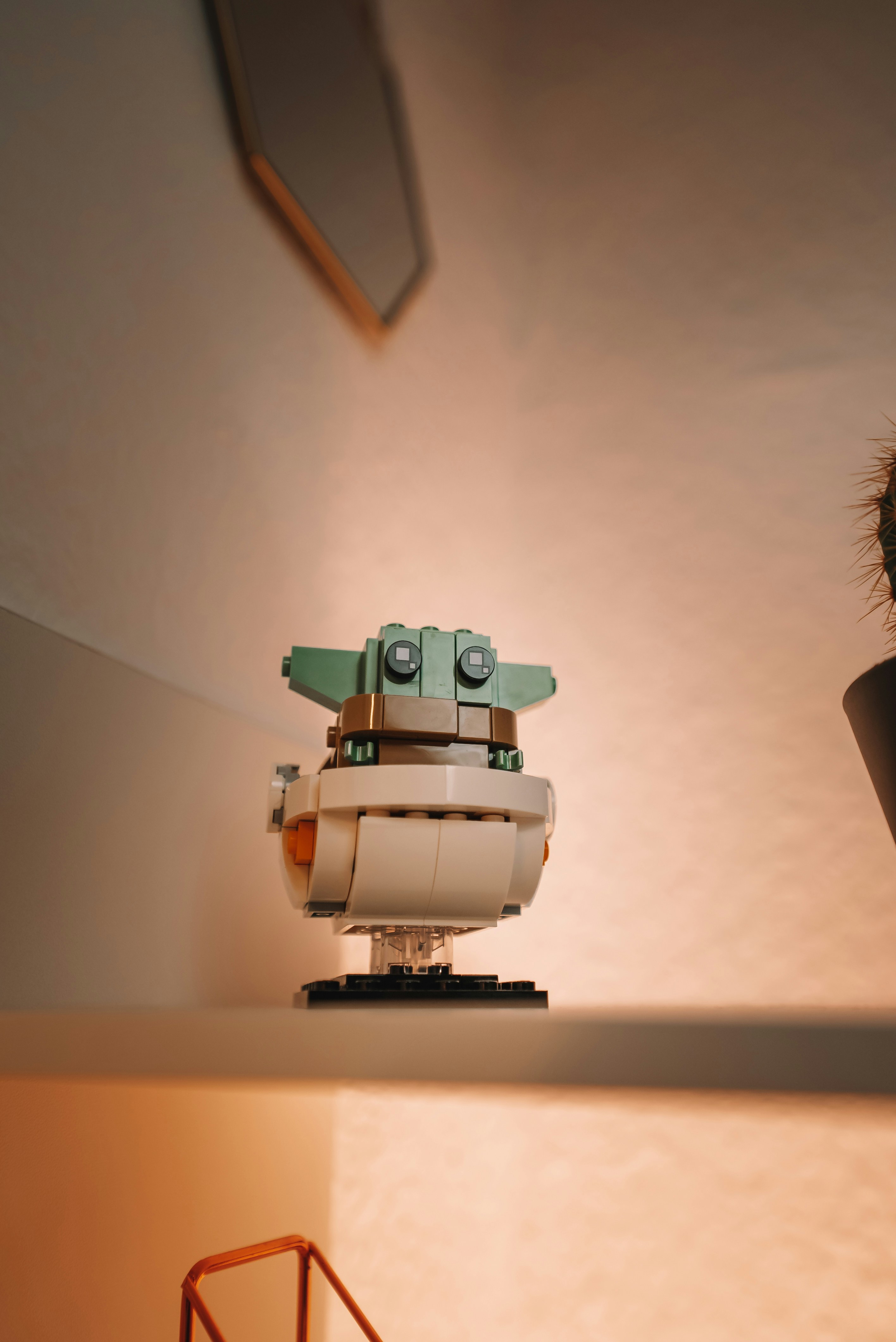 a lego robot sitting on top of a table next to a potted plant