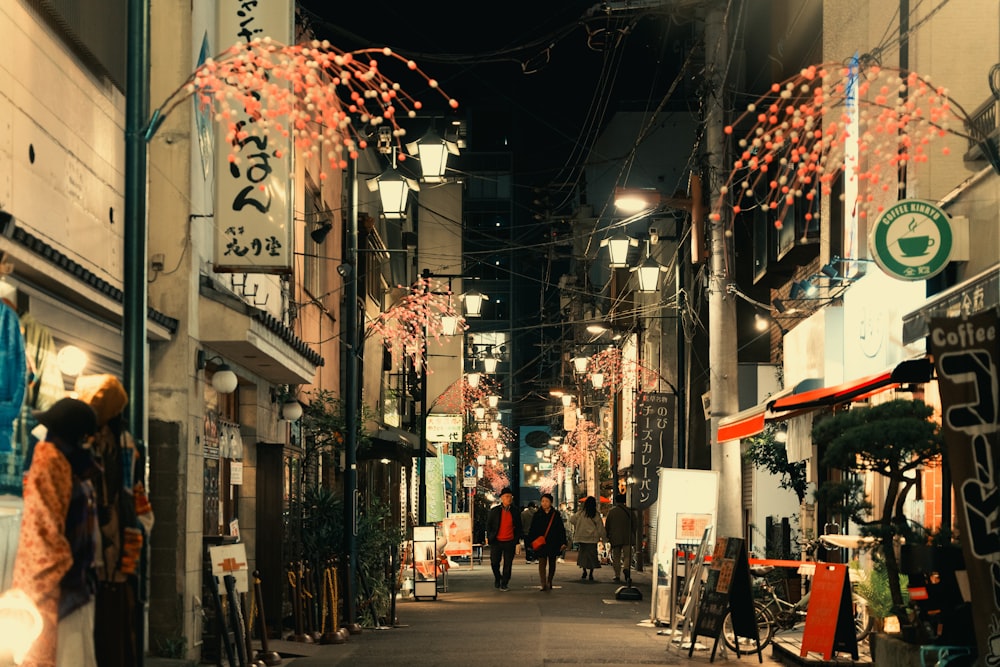 a narrow street with people walking down it at night