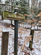 a no pathway sign in the woods covered in snow