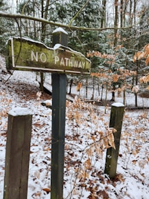 a no pathway sign in the woods covered in snow