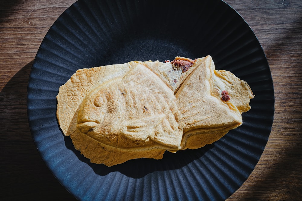 a black plate topped with a cut in half sandwich