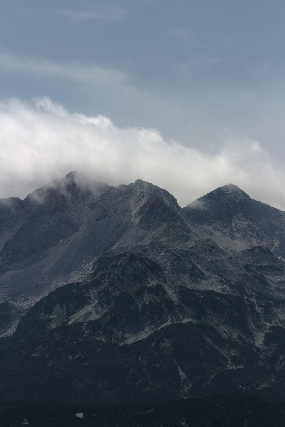 a mountain range with a few clouds in the sky