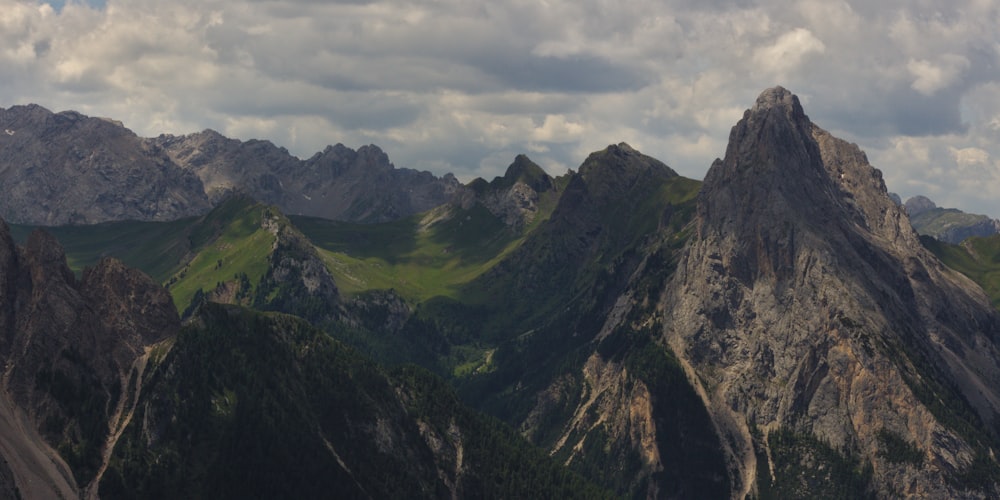 a group of mountains with a cloudy sky in the background