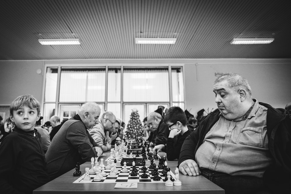 a group of people sitting at a table playing chess