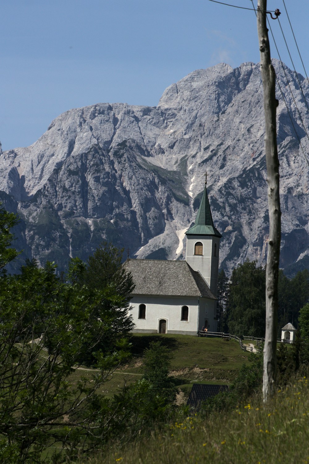 a white church with a steeple in front of a mountain range