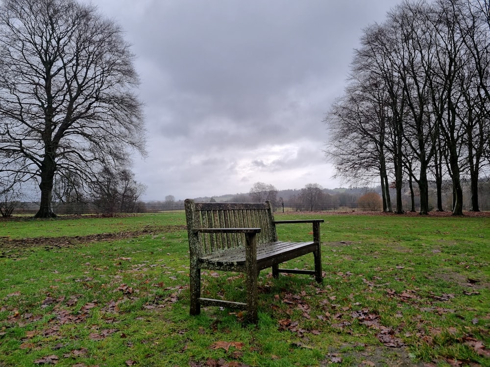 a wooden bench sitting in the middle of a field