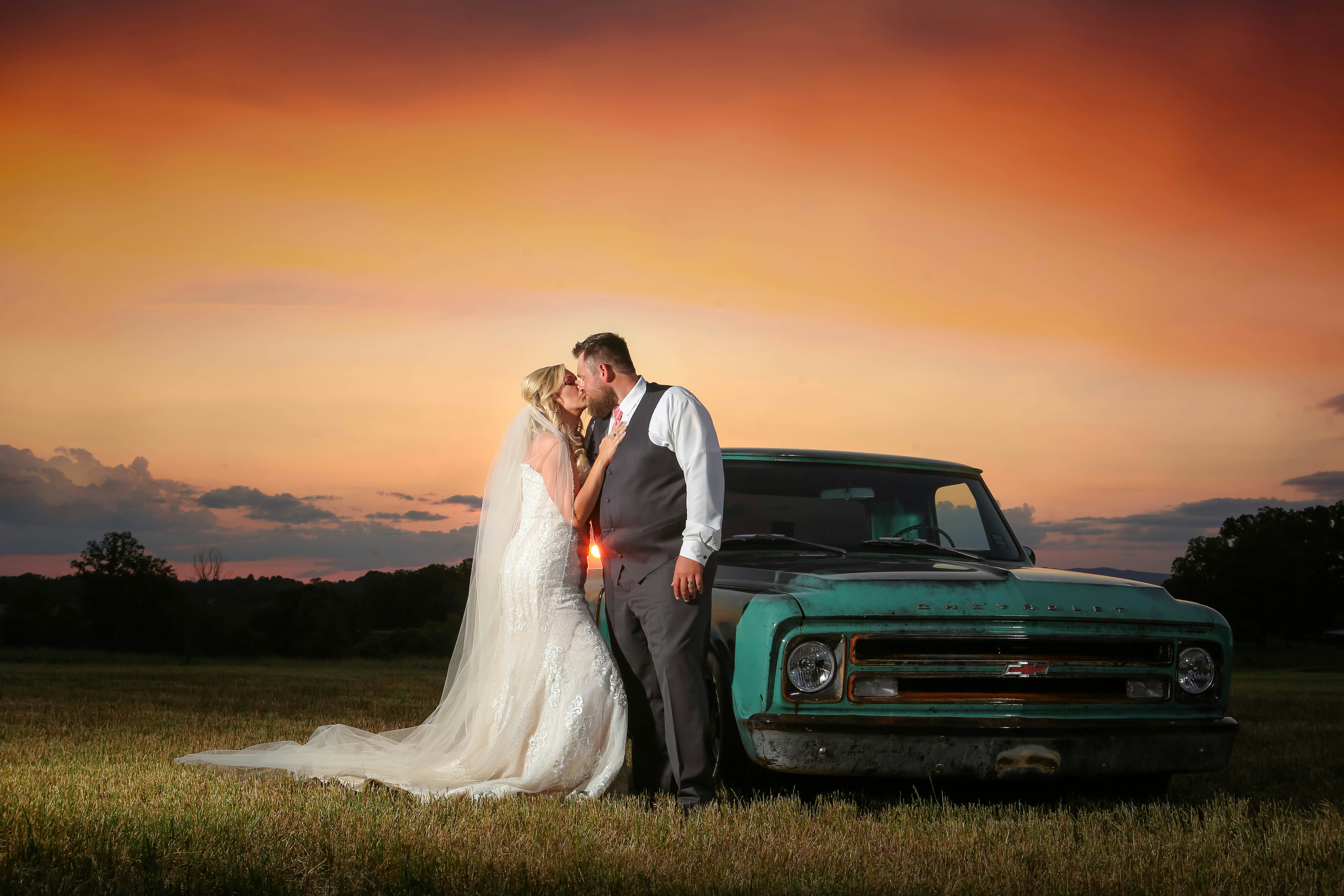 a bride and groom standing in front of a truck